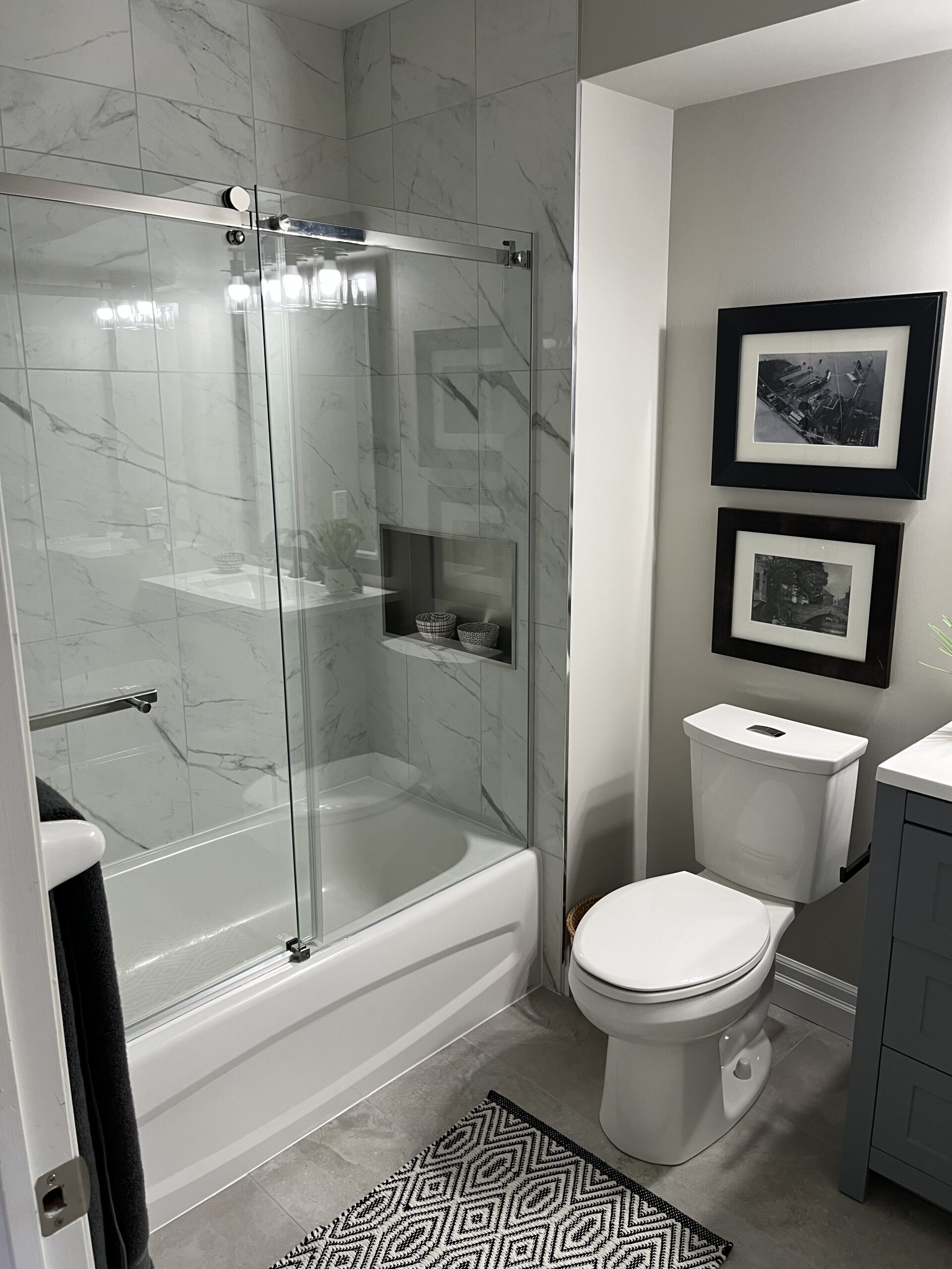 Finished bathroom renovation with glass shower and marble tile