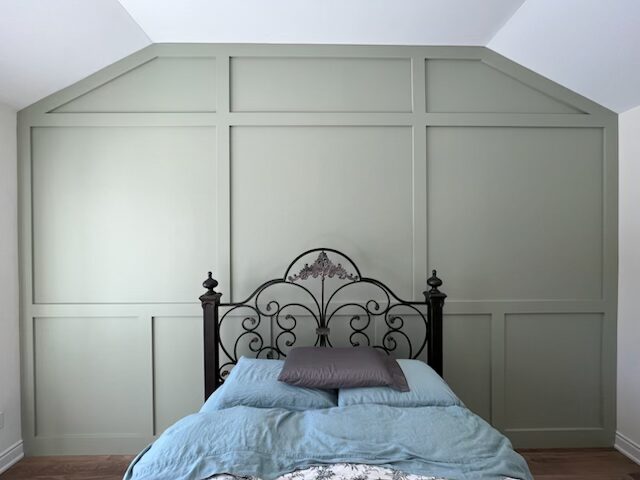Sage green board and batten accent wall behind a bed