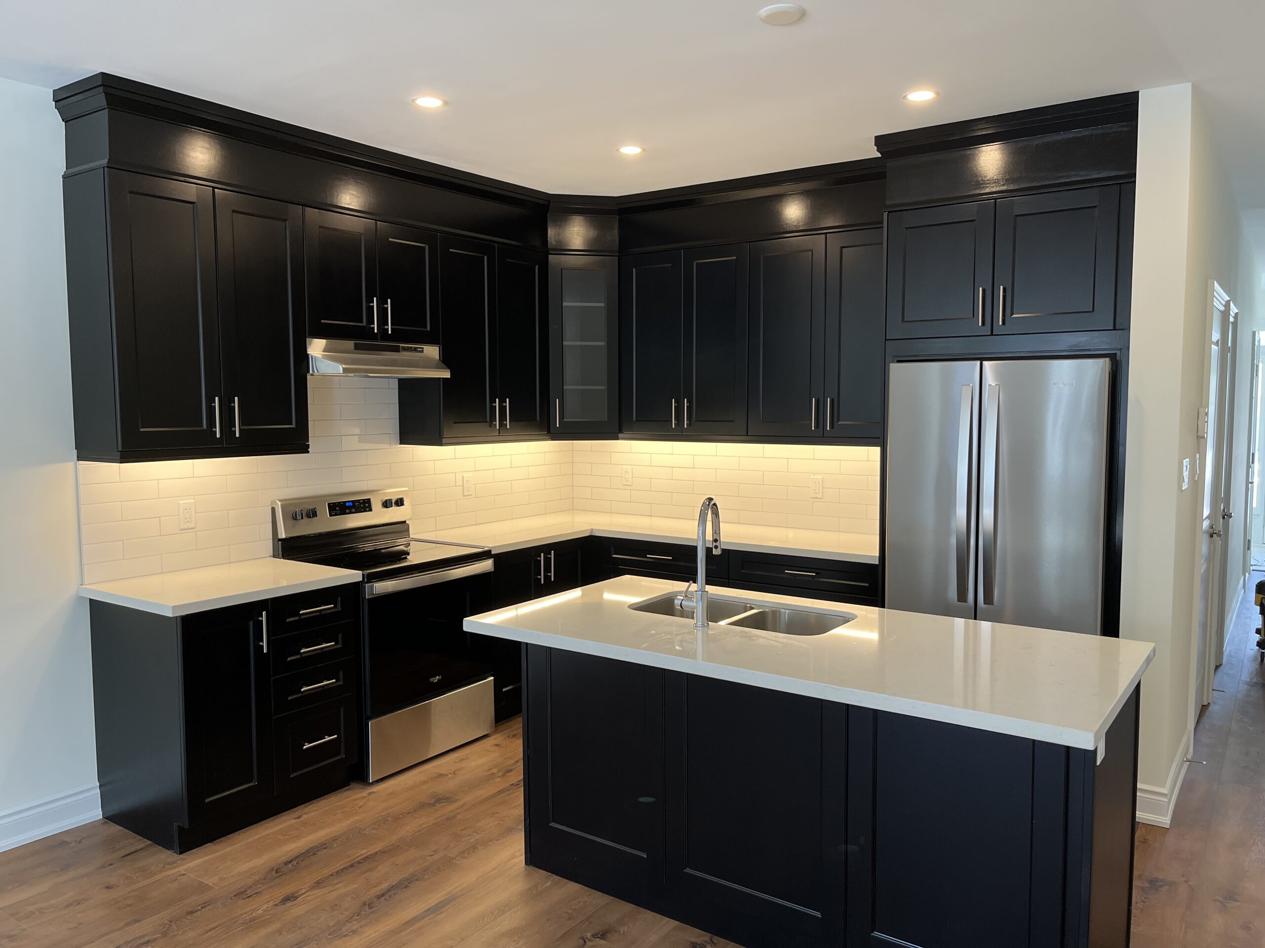 Renovated kitchen with black shaker cabinets, quartz counters and subway tile backsplash